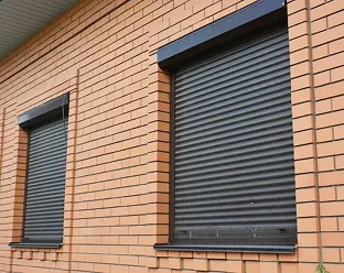 Zwarte rolluiken gemonteerd op witte gevel van een vrijstaand huis